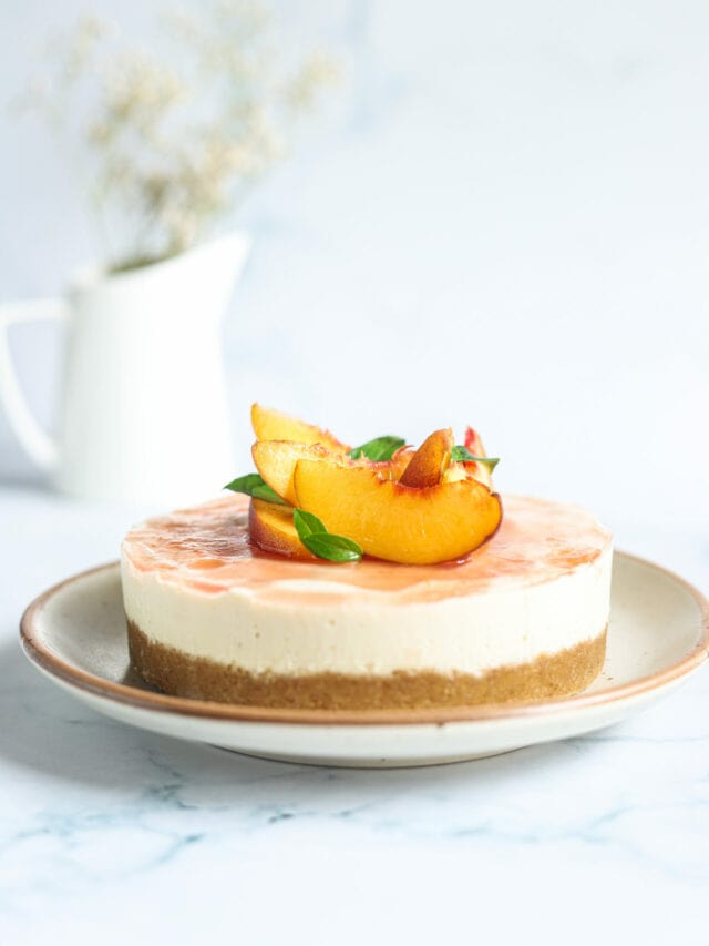 A slice of peach cheesecake on a white plate.