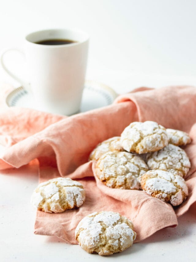 Crinkle cookies on a pink napkin next to a cup of coffee.