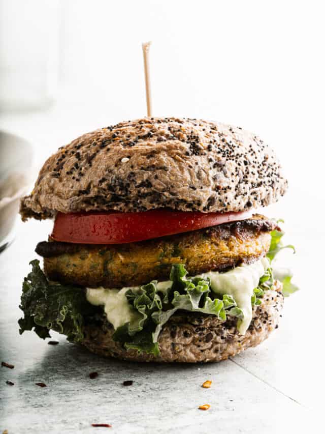 A vegetarian burger with a bean patty, tomato, lettuce, and sauce on a whole grain bun.