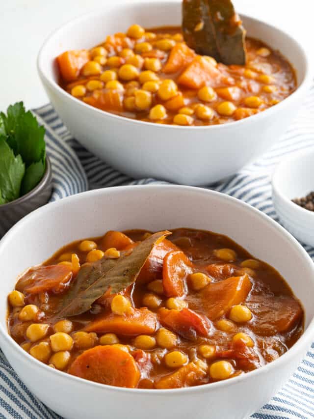 Two bowls of stew with carrots and chickpeas.