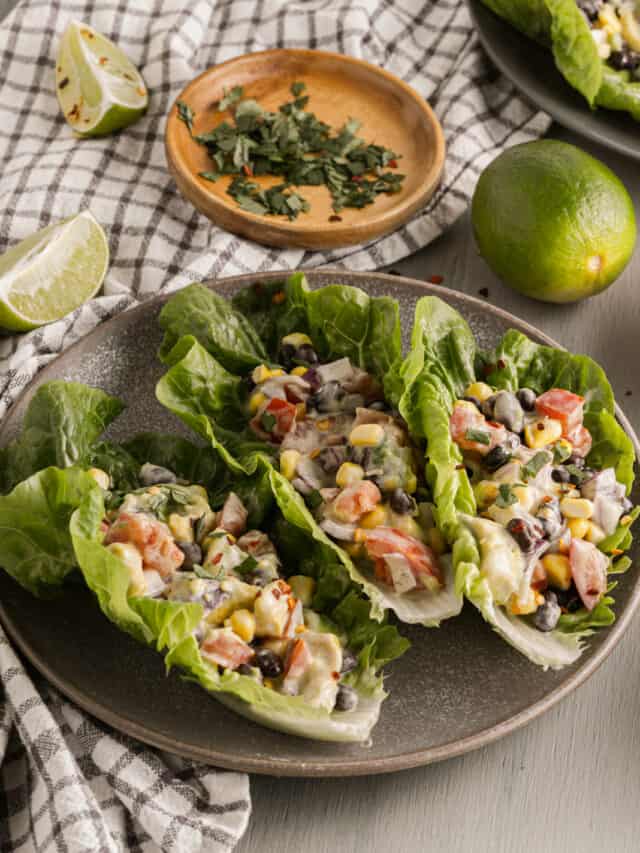 A plate with lettuce wraps and limes on it.