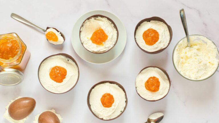 A group of bowls with easter eggs dessert and cream in them.