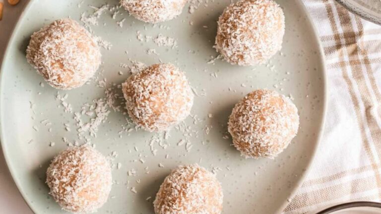 Coconut balls on a plate with a bowl of peanuts.