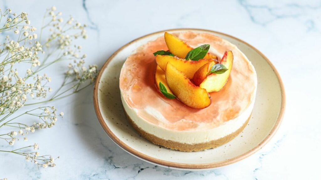 Peaches cheesecake on a white plate with flowers.