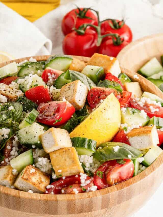 A bowl of tofu salad with tomatoes, cucumbers and lemons.