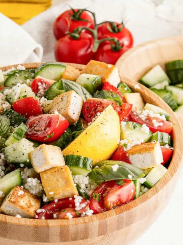 Tofu salad with tomatoes and cucumbers in a wooden bowl.
