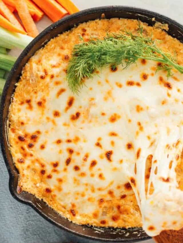 A cast iron skillet with a cheesy dip with carrots and celery.