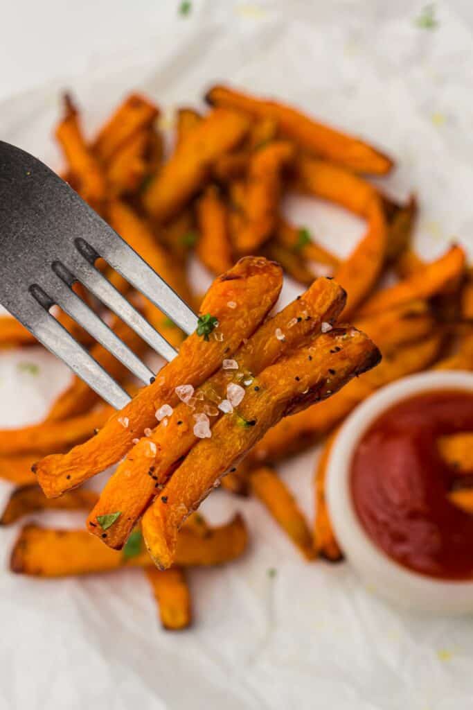 Sweet potato fries with ketchup on a fork.