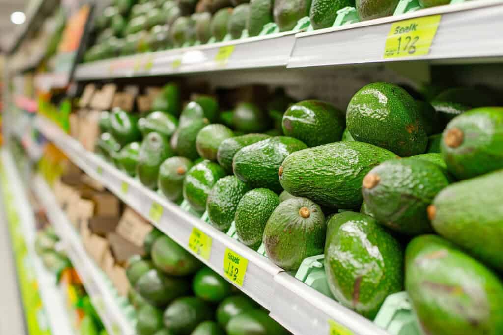 Avocados on shelves in a grocery store.