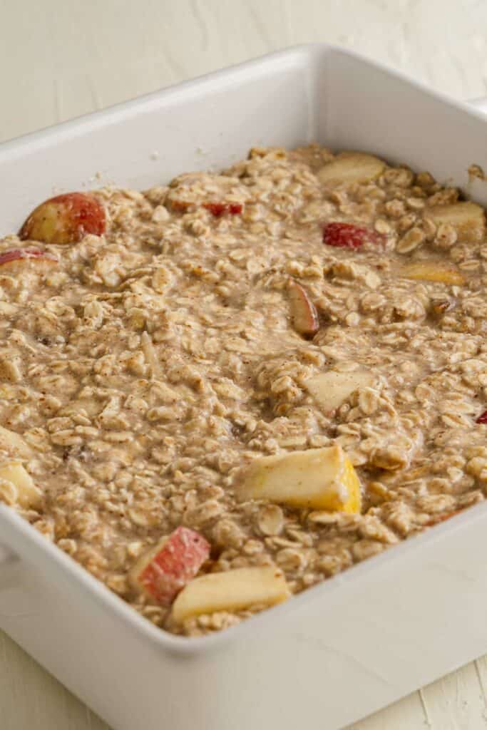 A white baking dish filled with oatmeal and apples.