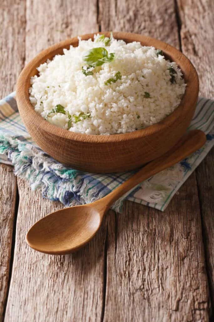White rice in a wooden bowl on a wooden table.
