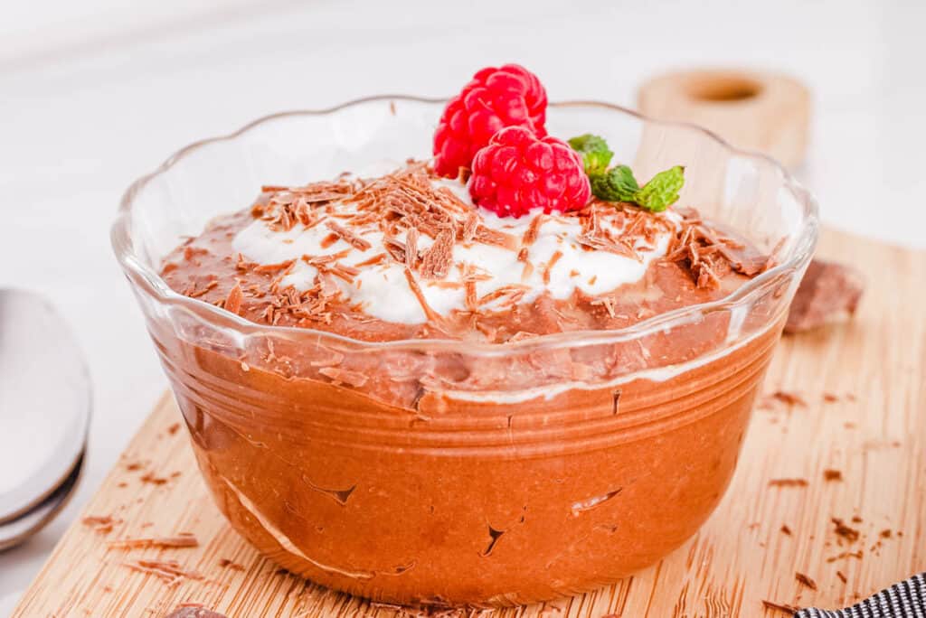 Chocolate coconut mousse in a glass with raspberries and whipped cream.