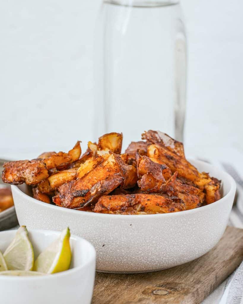 A bowl of crispy potatoes on a cutting board.