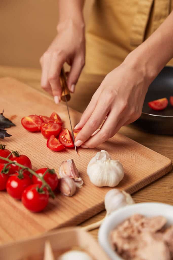 A woman is cutting tomatoes on a cutting board.