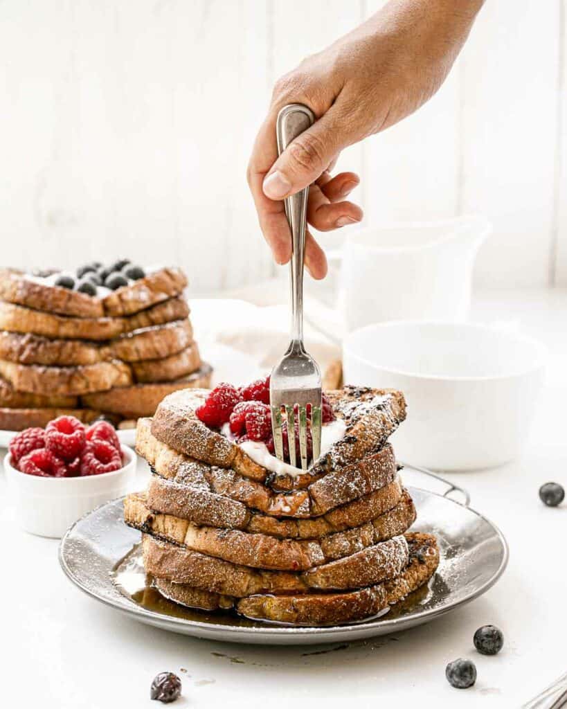 A stack of french toast with berries on a plate.