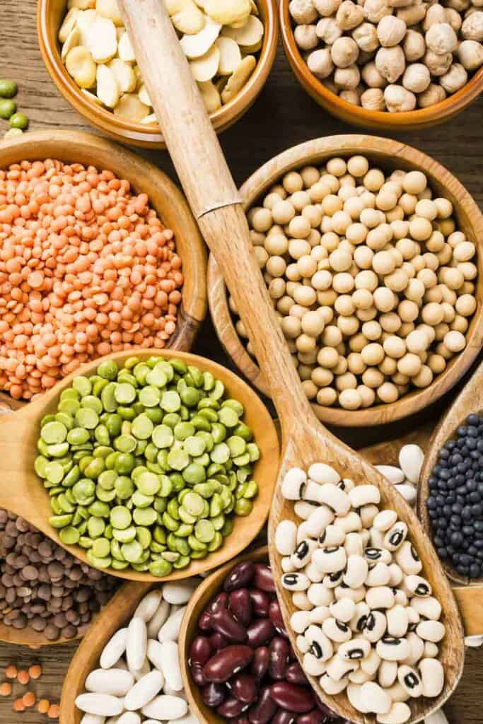 Various types of beans and legumes in wooden bowls.
