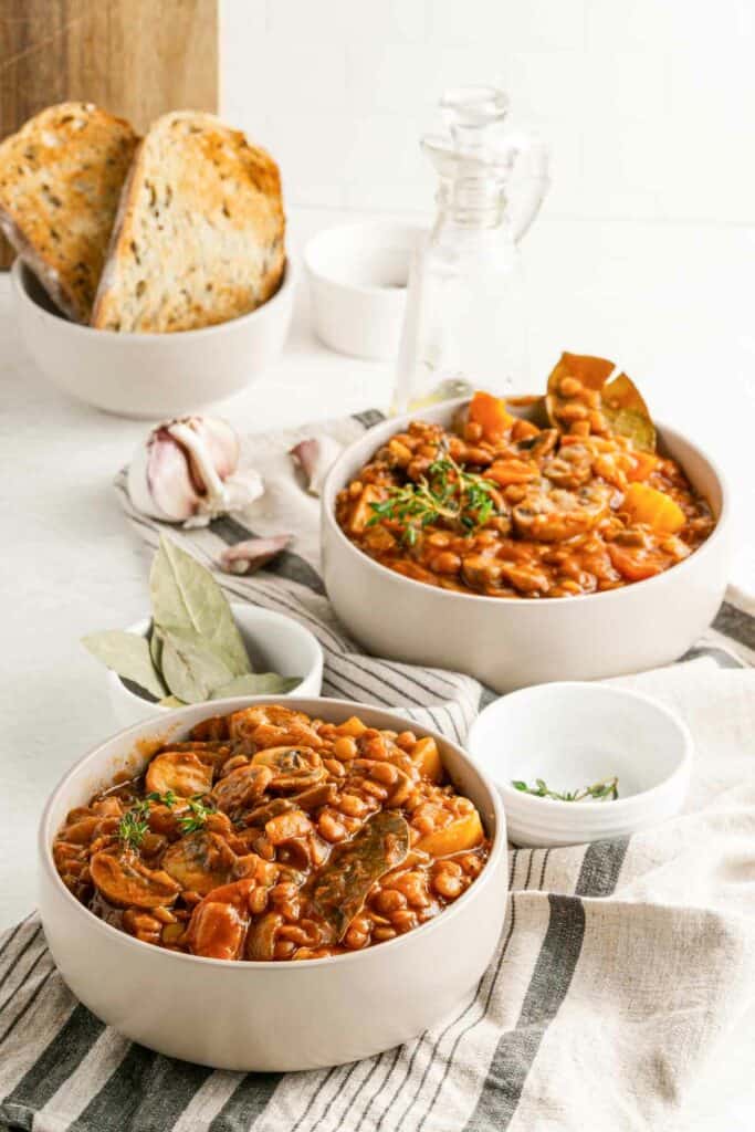 Two bowls of bean and mushroom stew on a table.