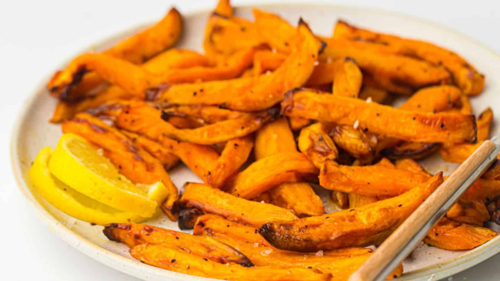 A plate of sweet potato fries with a wooden spoon.