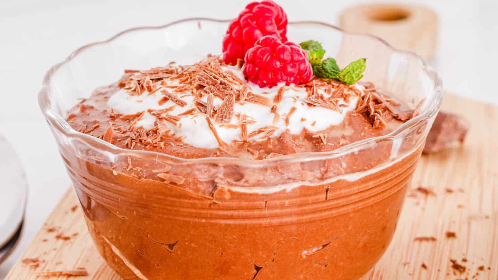 A bowl of chocolate mousse with raspberries and mint.