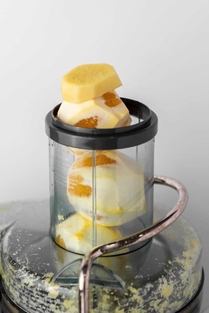 A citrus juicer with peeled lemons, oranges, and ginger in it.