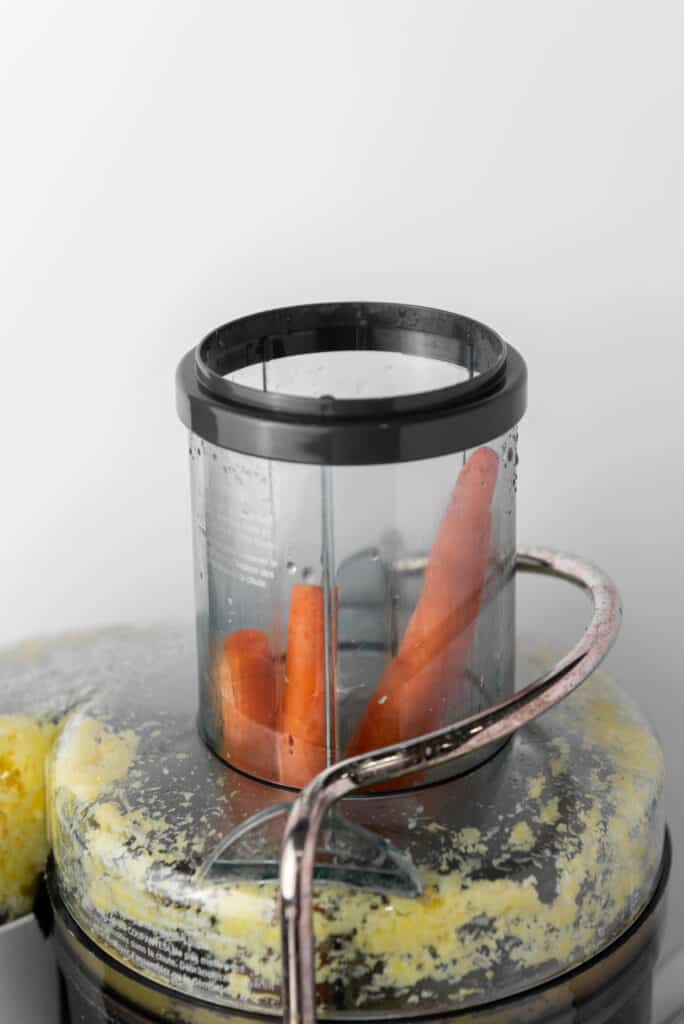 A food processor with carrots in it.