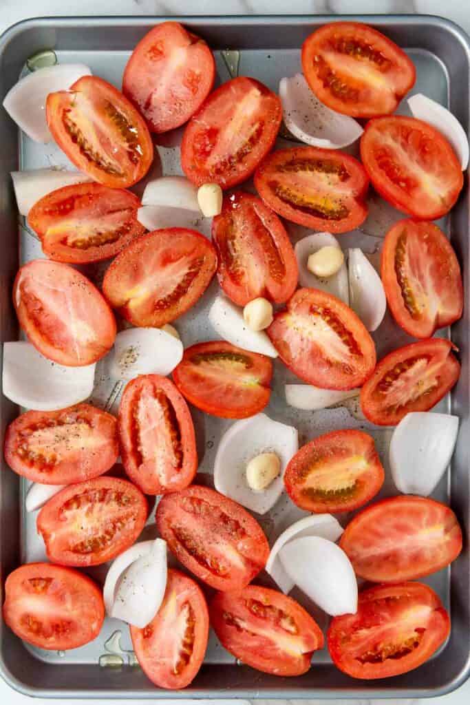 Tomatoes and garlic on a baking sheet, perfect for creating delicious Roasted Tomato Basil Soup.