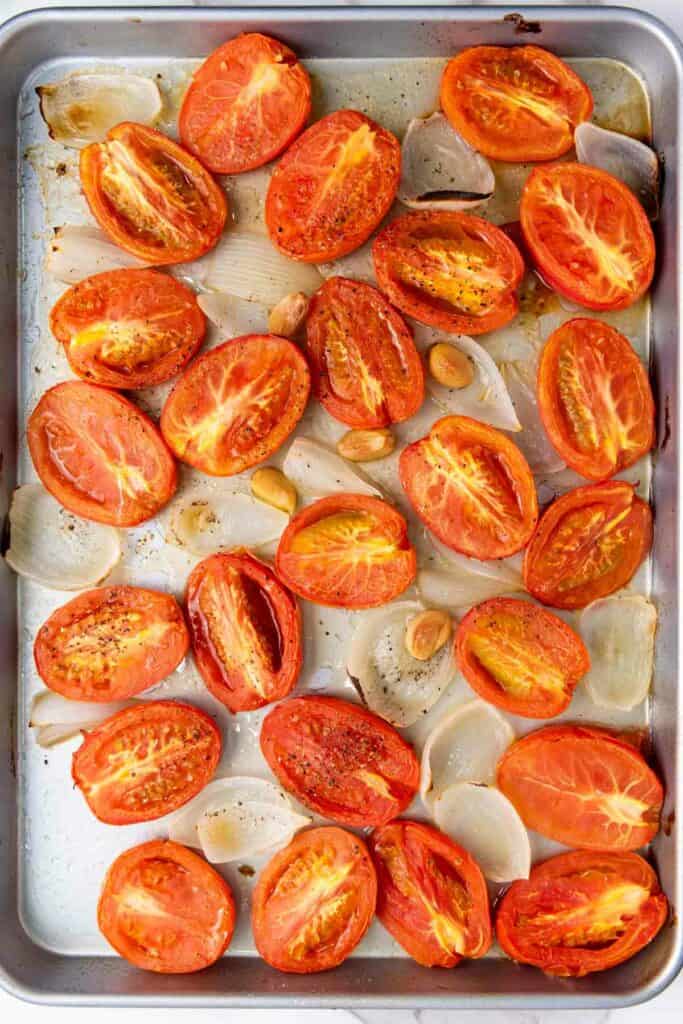 Roasted tomato slices and caramelized onions on a baking sheet.
