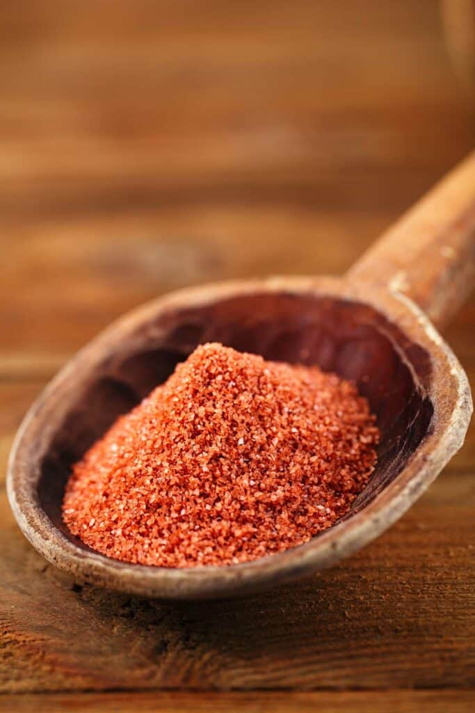 Red salt in a wooden spoon on a wooden table.