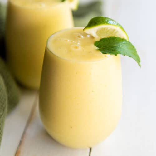 A refreshing tropical smoothie recipe with the perfect combination of lime and mint leaves, served in two glasses.