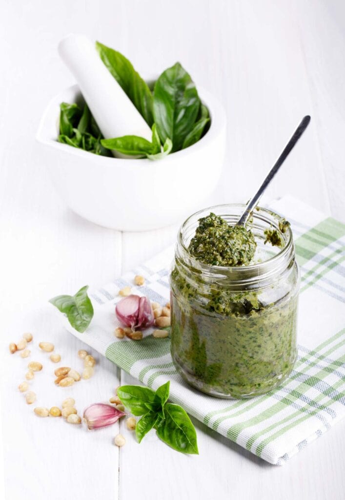 Pesto sauce in a jar on a wooden table.