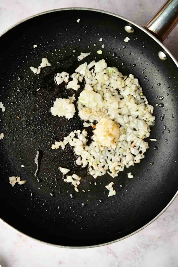A skillet with garlic and onion.