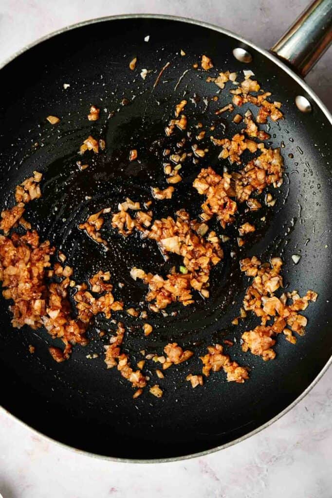 A skillet with garlic and spices in it.