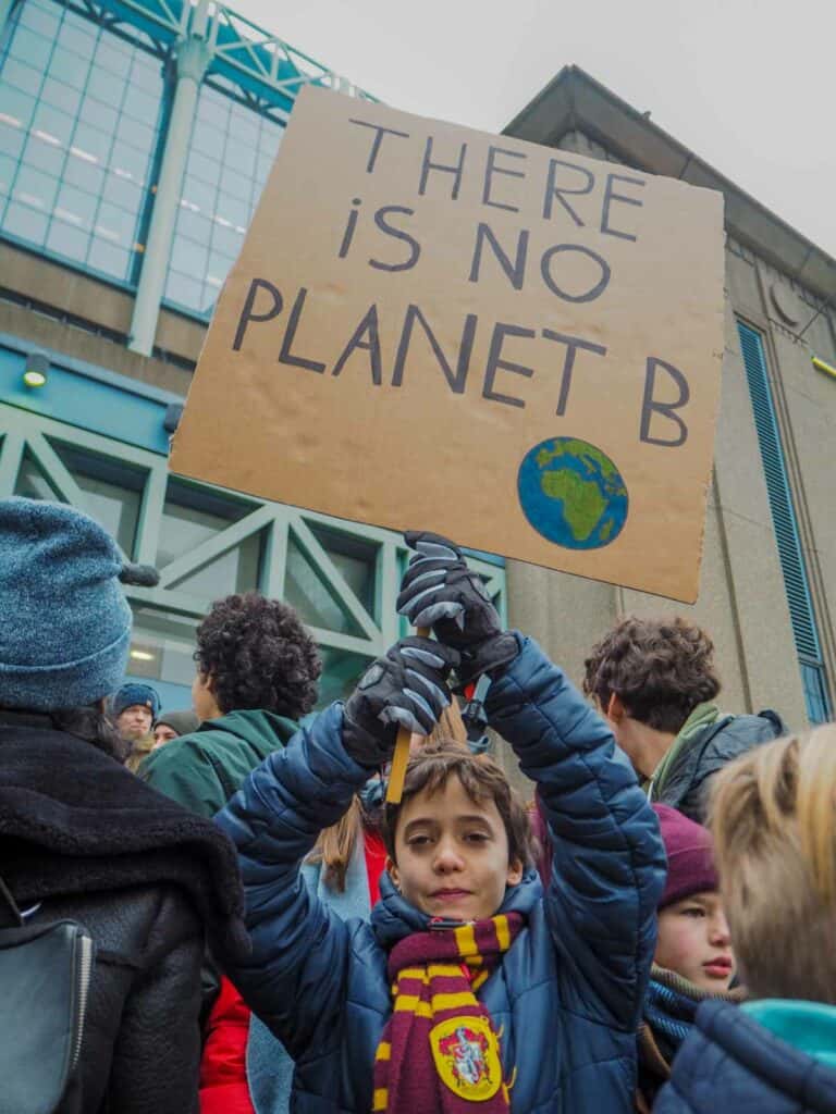 A boy holds up a sign that says there is no planet b.