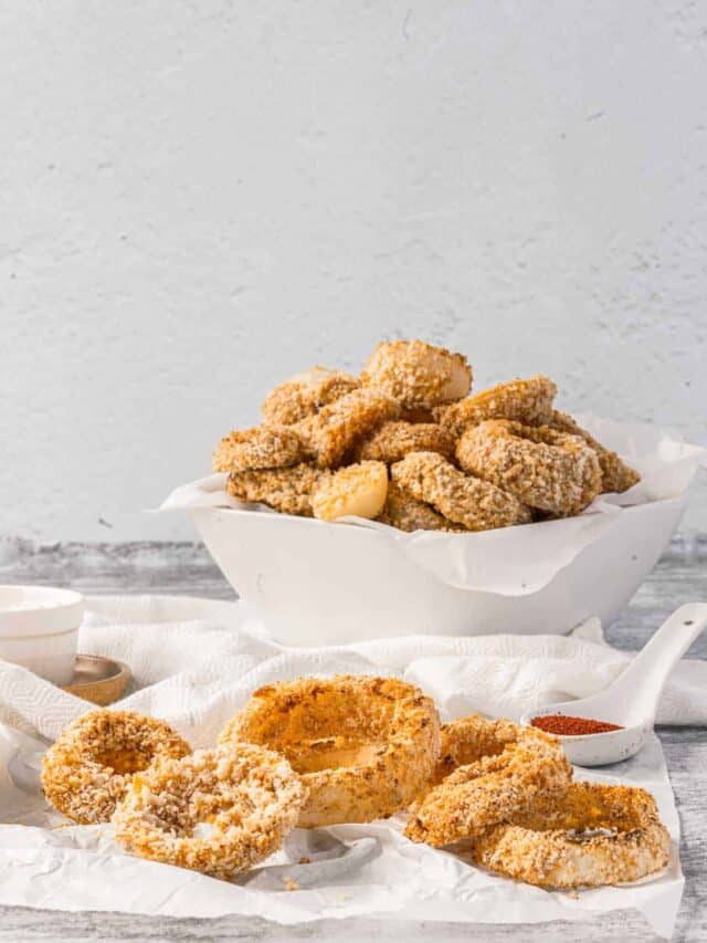 Fried onion rings in a bowl on a white table.