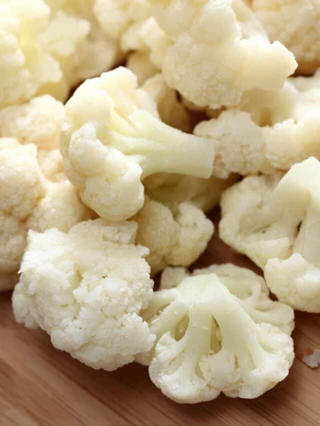 A pile of cauliflower on a wooden surface.