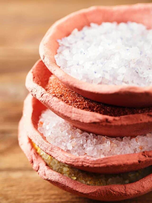 Three bowls of sea salt on a wooden table.