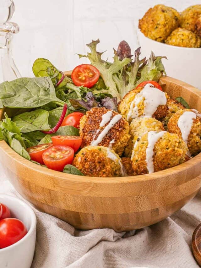 A wooden bowl filled with meatballs and salad.