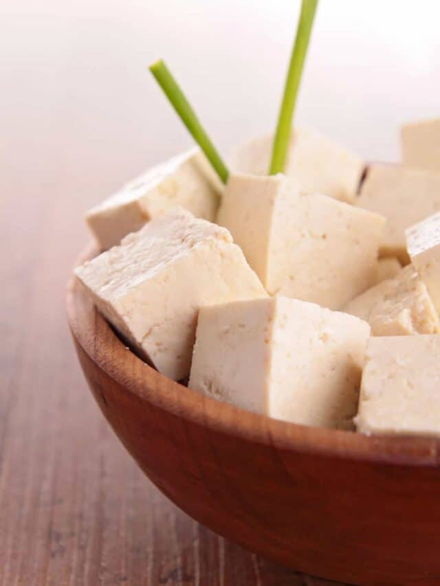 A bowl of cubed tofu on a wooden surface.