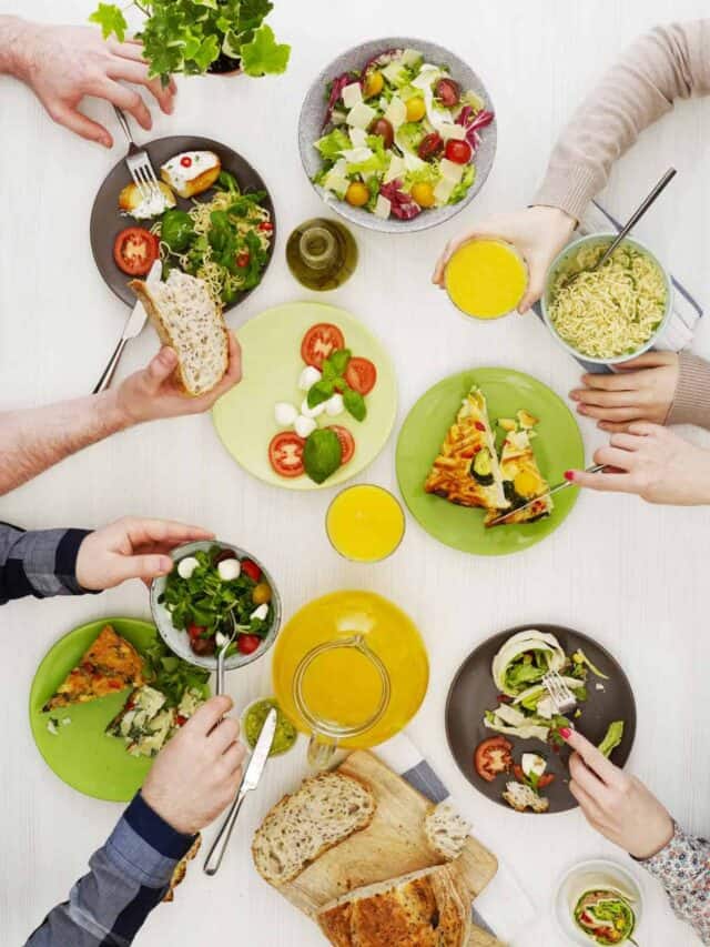 A group of people sitting around a table with plates of food.