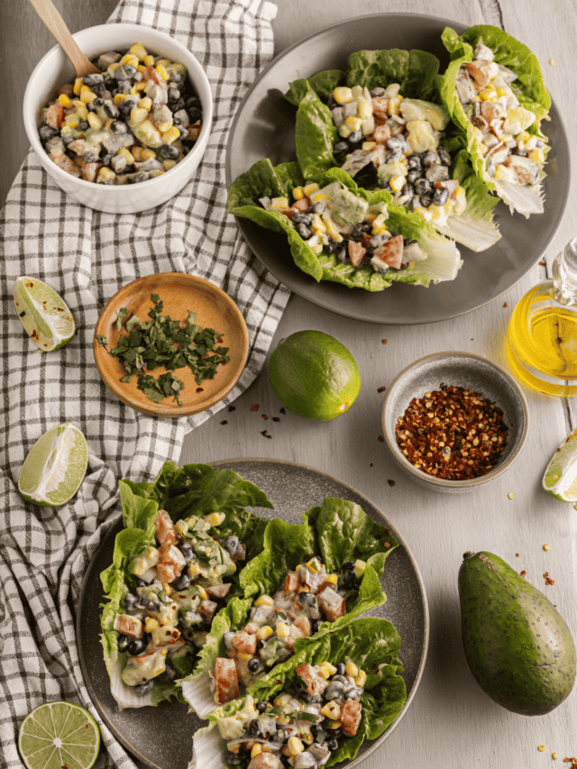 A plate of lettuce wraps with black beans, corn and limes.