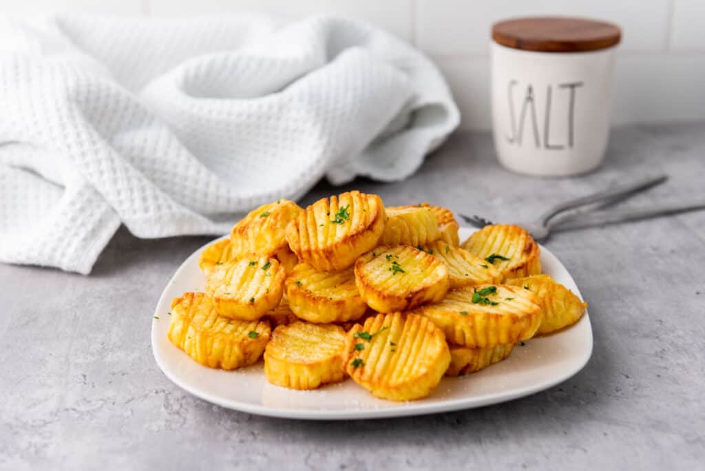 Air fryer roasted accordion potatoes on a plate with salt and a fork.