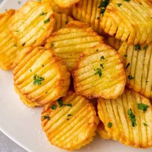 Crispy accordion potatoes served on a plate with a hint of parsley.
