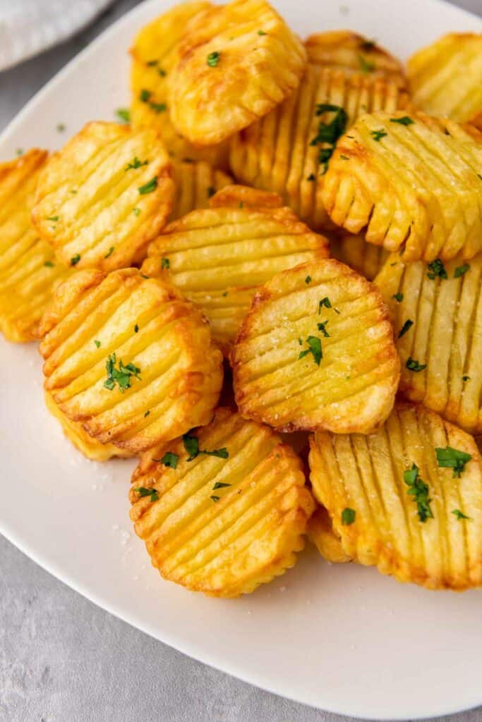 Crispy potato chips served on a plate with a hint of parsley.