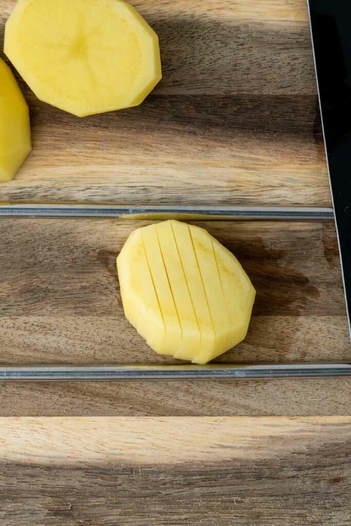 A slice of potato on a cutting board being prepared for the air fryer.