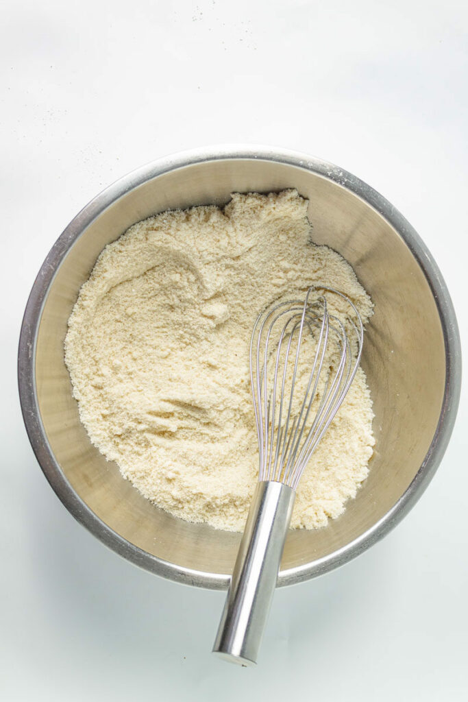 A whisk in a bowl of flour.