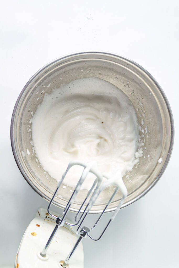 Whipped cream in a bowl with a whisk.