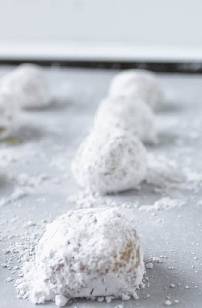 Powdered sugar cookies on a baking sheet.