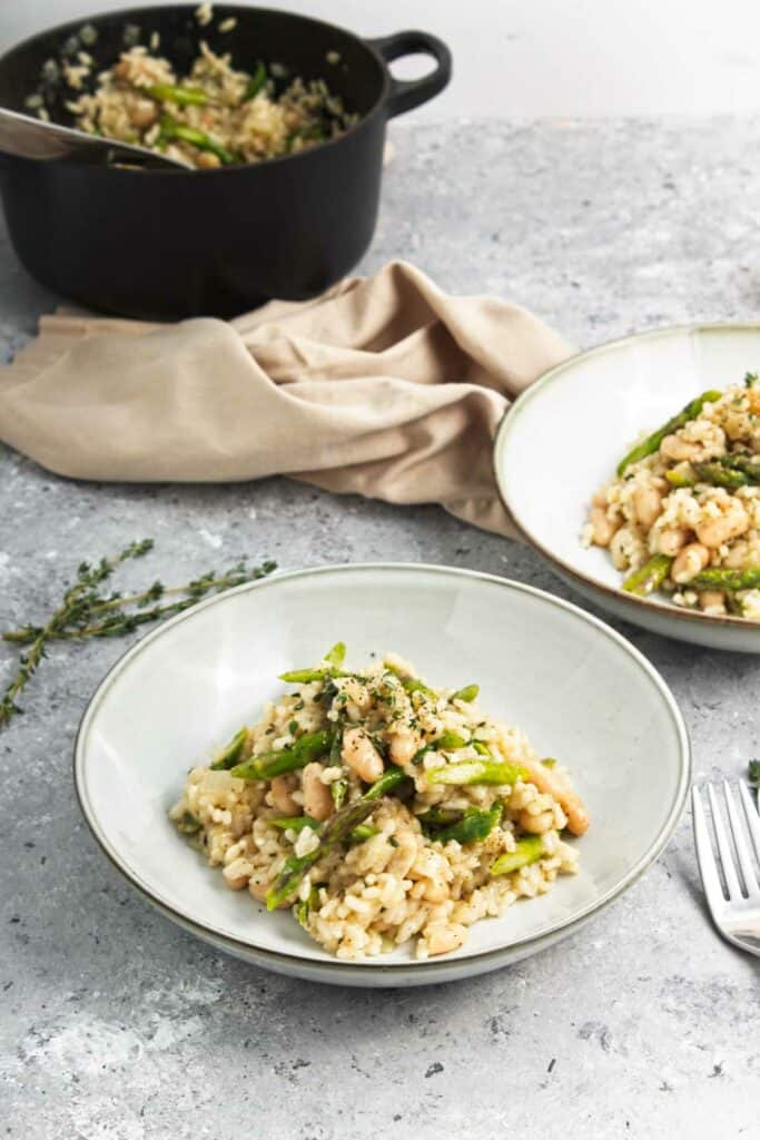 Two plates of Asparagus and White Bean Risotto with nuts.