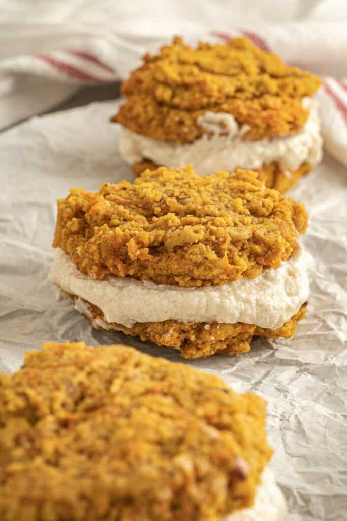 A stack of pumpkin cookies on top of a piece of parchment paper.