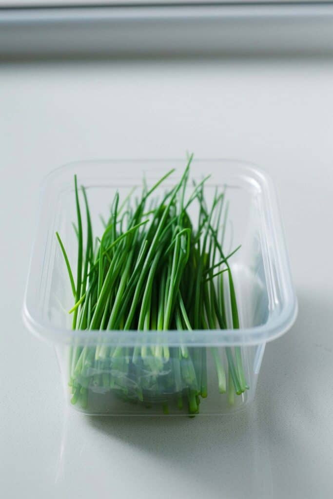 A plastic container with a bunch of greens in it.